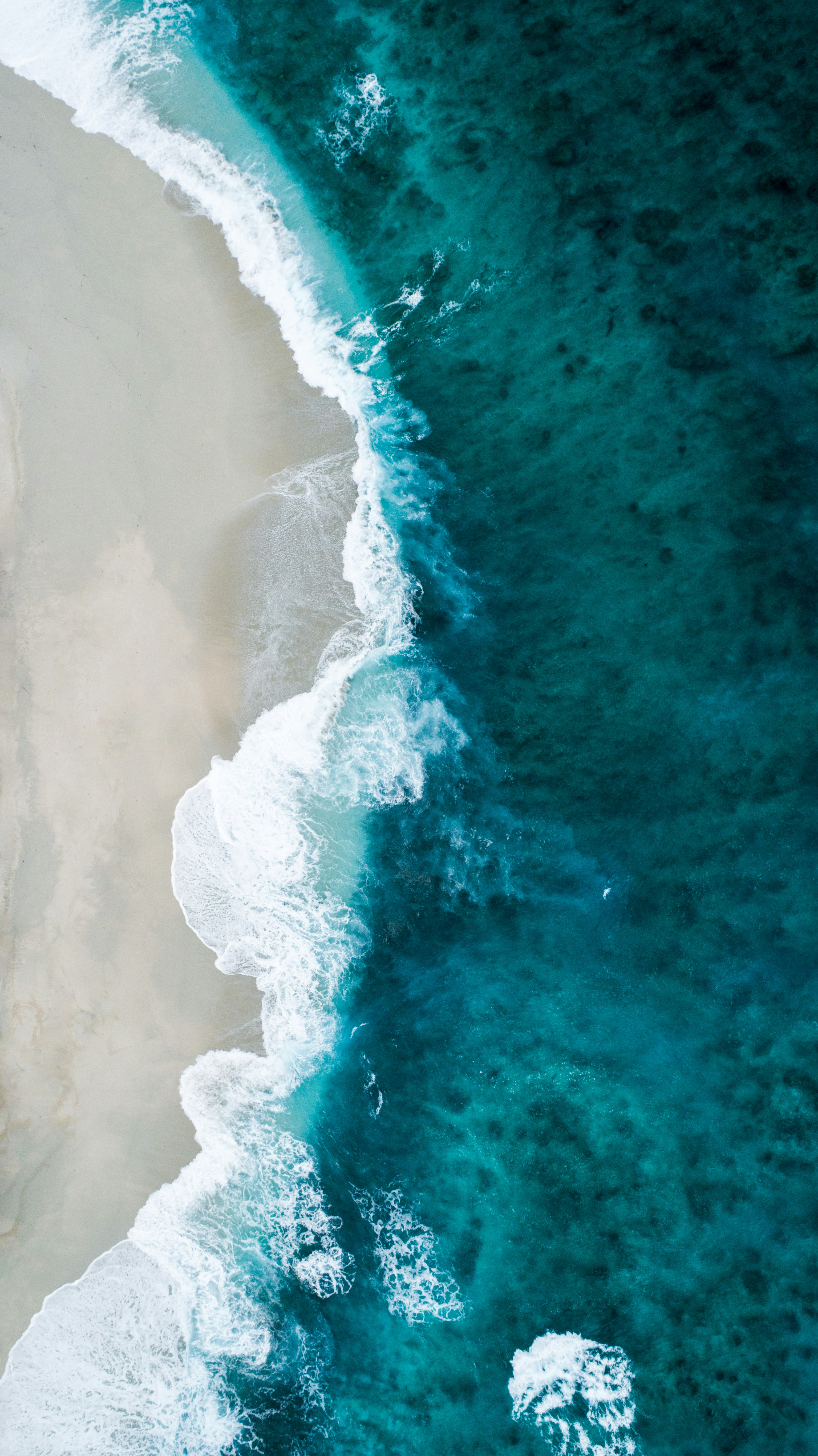 Aerial view of turquoise ocean surf meeting the shore