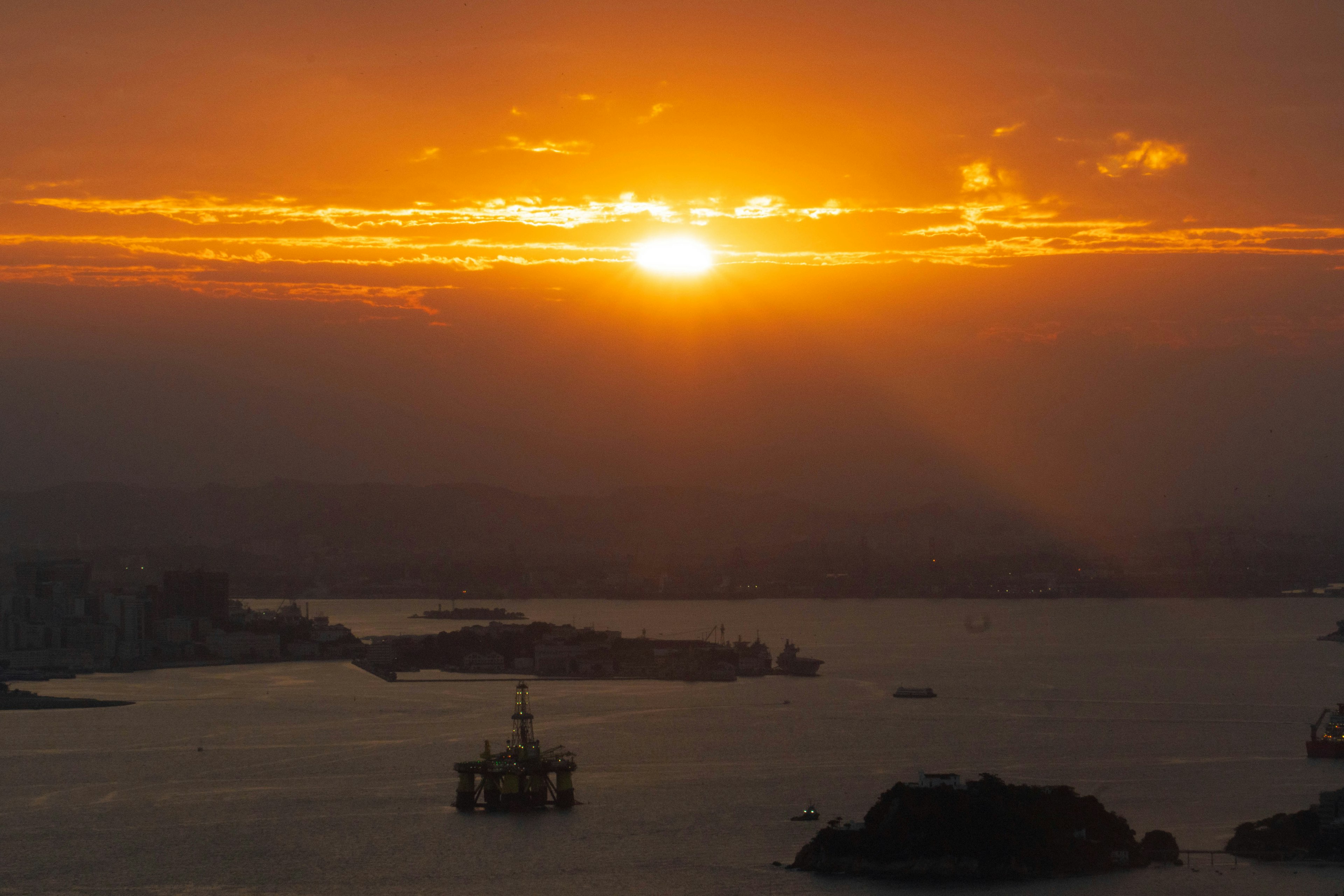 Offshore platform silhouetted against a dramatic ocean sunset